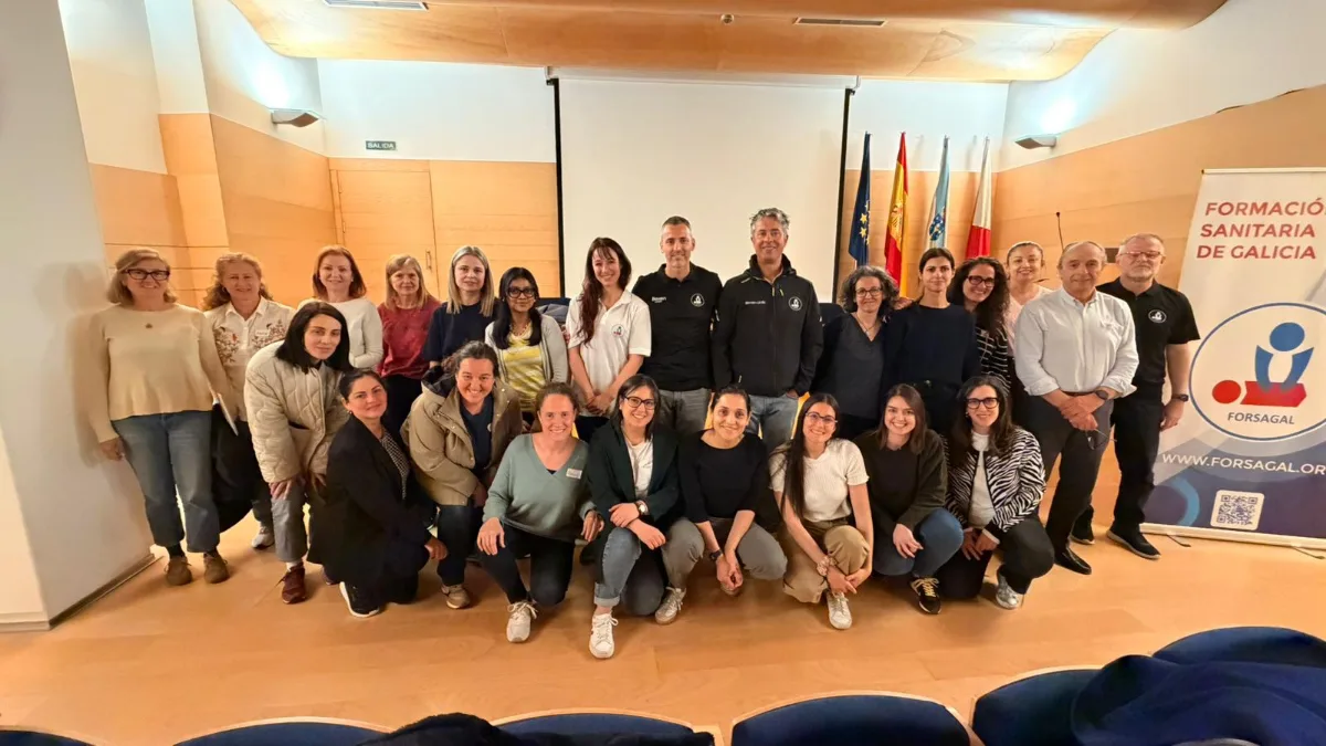 Participantes y docentes de un curso de soporte vital básico junto al cartel de FORSAGAL.